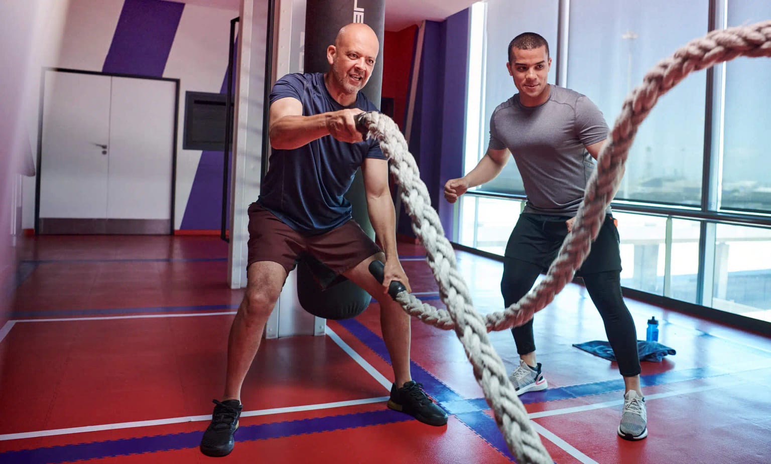 A man works with a personal trainer with rope at a Virgin Active gym.